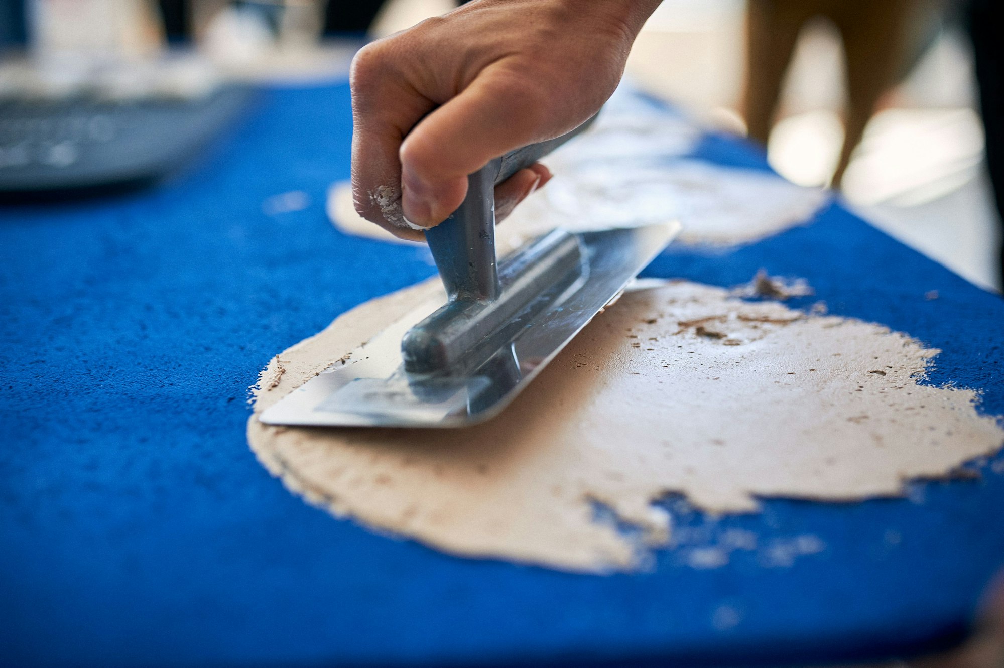 Man hand with trowel plastering a blue surface